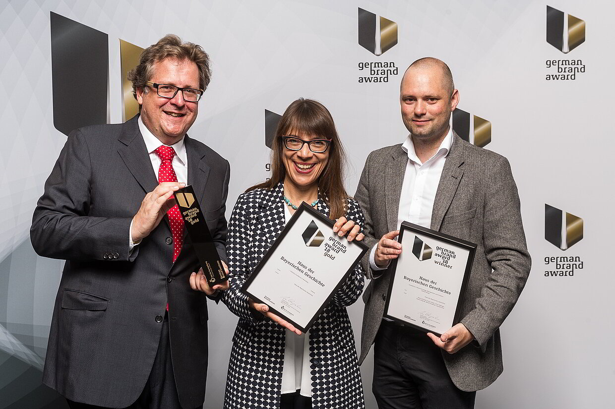 Am 21. Juni 2018 wurde dem Haus der Bayerischen Geschichte vom Rat für Formgebung in Berlin die Gold-Auszeichnung in der Kategorie „Industry Excellence in Branding – Culture“ feierlich überreicht. Glückliche Gewinner (v. l. n. r.): Dr. Richard Loibl, Direktor Haus der Bayerischen Geschichte, Natascha Zödi-Schmidt, Stabsstellenleitung Kommunikation Haus der Bayerischen Geschichte, und Ulrich Aldinger, Creative Director Peter Schmidt Group GmbH
