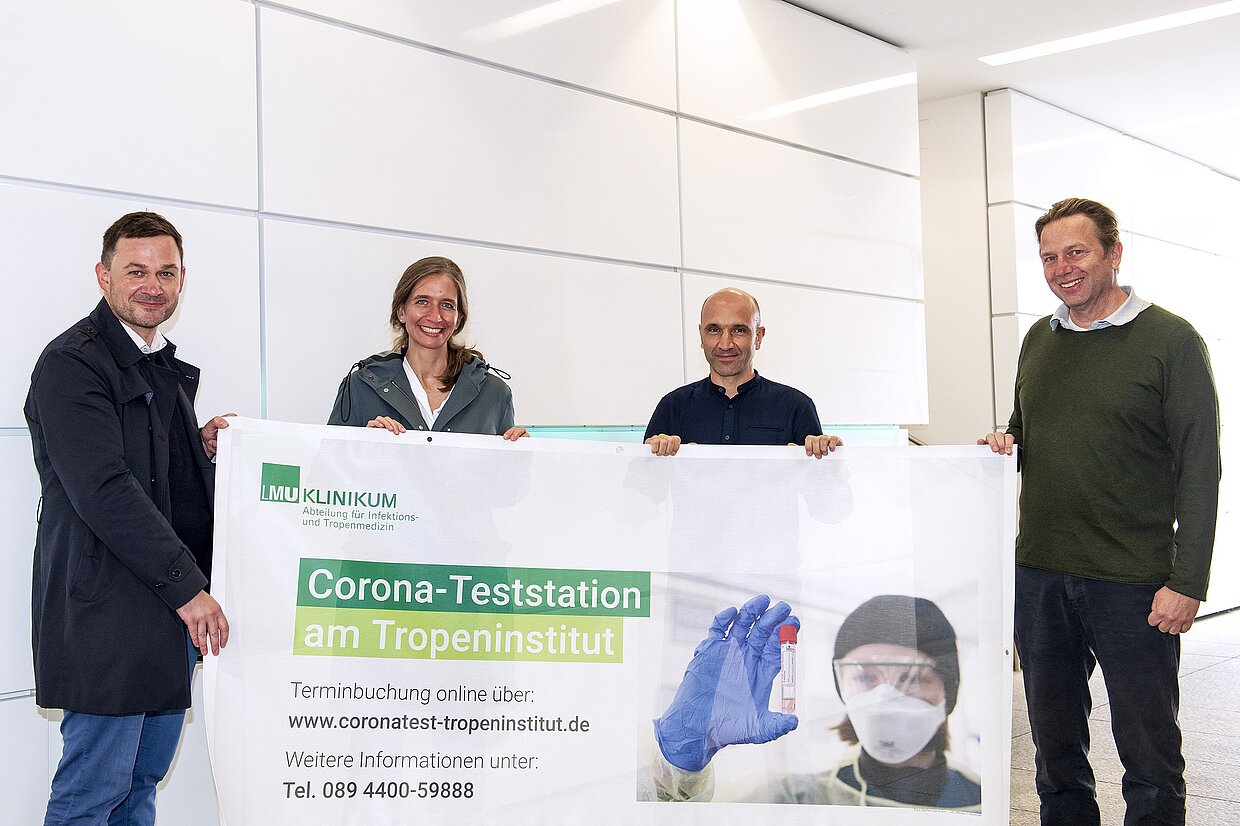 v.l.n.r. Dr. Nüßlein (HdBG), Dr. med. Rothe, Dr. med. Fröschl und Prof. Dr. med. Hoelscher bei der Übergabe der Exponate (im Bild: Infobanner) des Münchner Tropeninstituts. © LMU Klinikum München/Steffen Hartmann