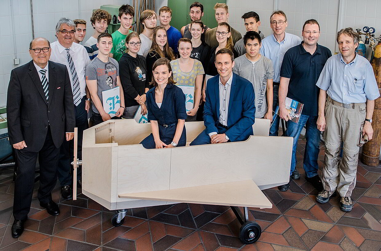 Stolz auf das selbstgebaute Flugzeug: Die Schüler der Klasse 11 Ta der Fachoberschule Cham und die Schreiner-Ausbilder Peter Zimmermann (3. v. r.) und Martin Schumann (rechts) sowie Metall-Ausbilder Horst Rettinger (2. v. r.), Dr. Andreas Kuhn und Mariella Hosp vom Haus der Bayerischen Geschichte (im Modell sitzend), Kammer-Hauptgeschäftsführer Toni Hinterdobler (1. v. li.) und Bildungszentrumsleiter Josef Ramsauer (2. v. li.).