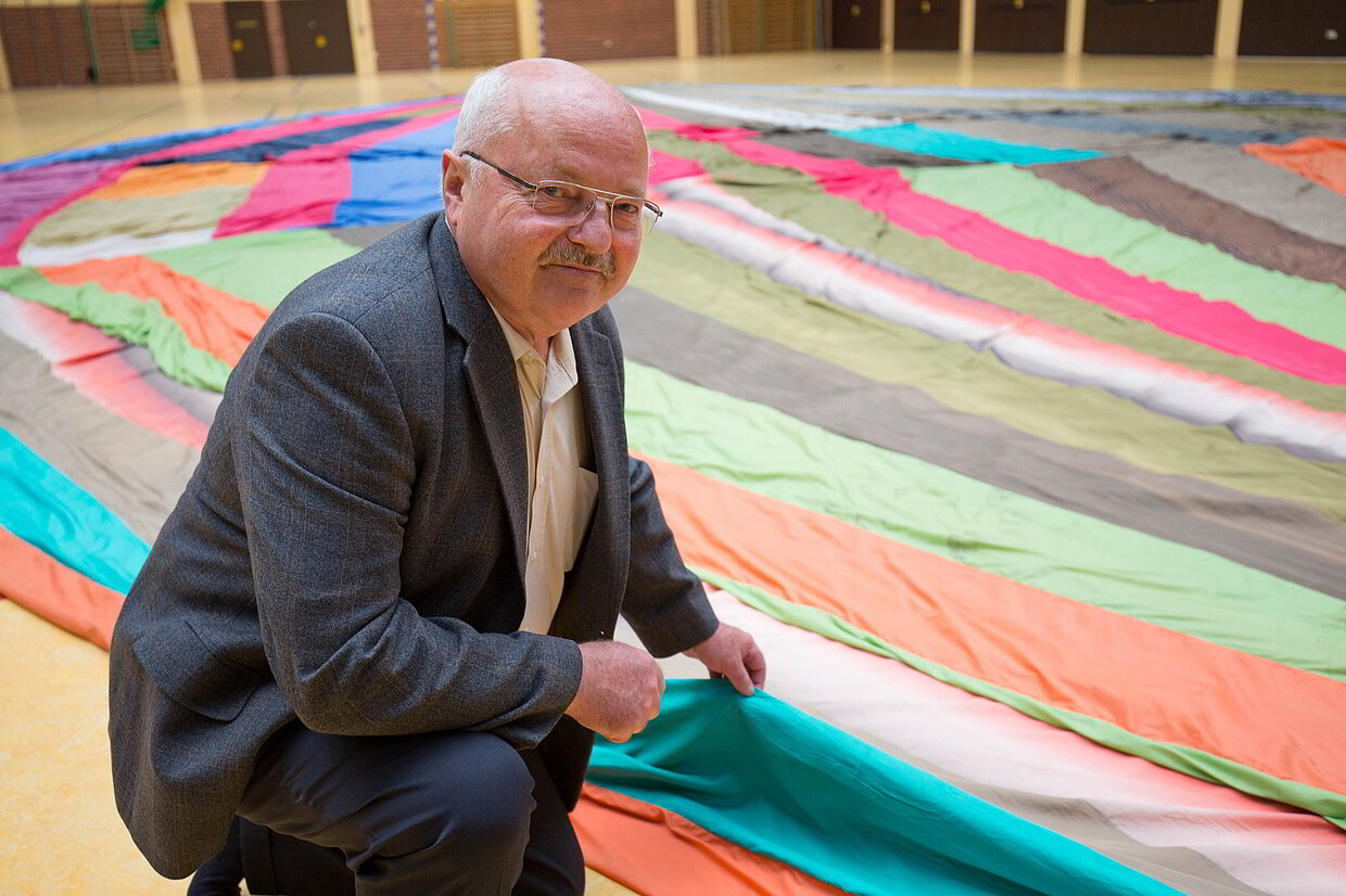 Zeitzeuge Günter Wetzel kniet vor dem selbstgebauten Heißluftballon, mit ihm 1979 die Flucht über die innerdeutsche Grenze gelang. 