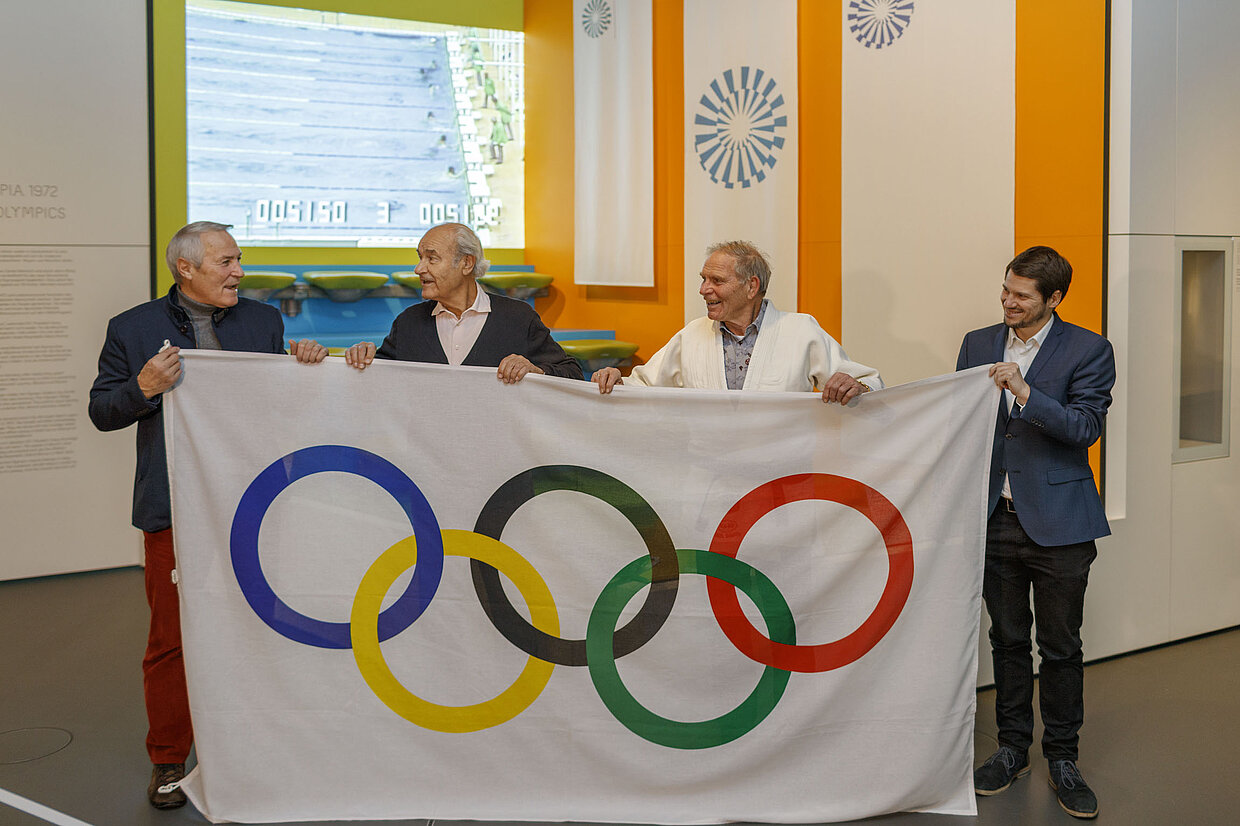 Objektübergabe zur Sonderausstellung „Bayern und Olympia 1896 - 2022“ (v.l.n.r.) Alois Schloder, Manfred Schnelldorfer und Paul Barth mit dem Referenten für Ausstellungen im Museum Marc Spohr.