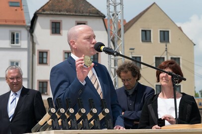 Regensburgs Oberbürgermeister Joachim Wolbergs gibt der Zeitkapsel für den Museumsgrundstein eine eigens angefertigte Kunstmedaille hinzu, die Regensburg als erste Hauptstadt Bayerns ausweist.